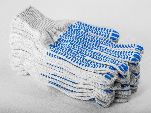 Weiße Baumwollhandschuhe mit blauen Gumminieten auf weißem Hintergrund lizenzfreie Stockbilder