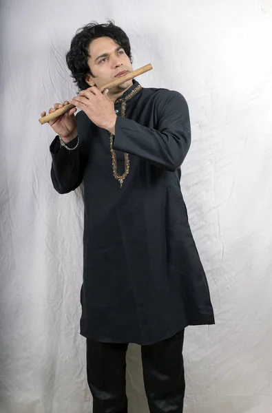 indian male model in black kurta playing flute
