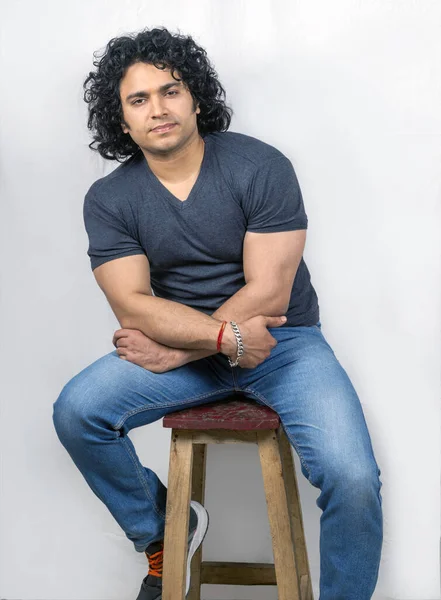 young indian male model wearing grey tshirt sitting