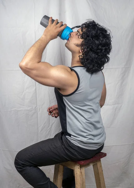 indian male model wearing silver vest drinking protein