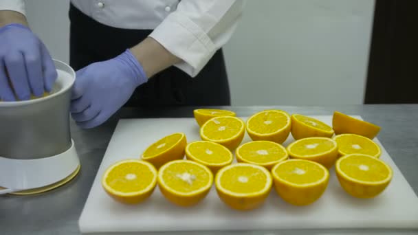 El cocinero cocina jugo de naranja en el extractor de jugo . — Vídeos de Stock