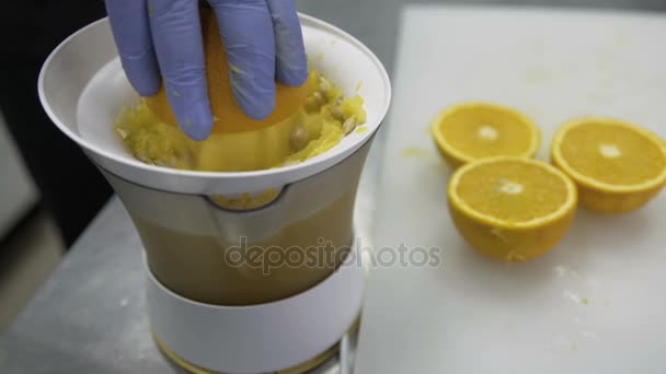 El cocinero cocina jugo de naranja en el extractor de jugo . — Vídeo de stock