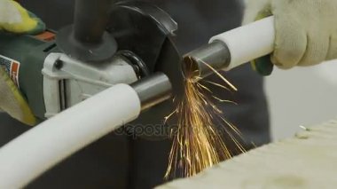 İşçi eldiven bir metal boru iki parça halinde açı öğütücü ile kesme.