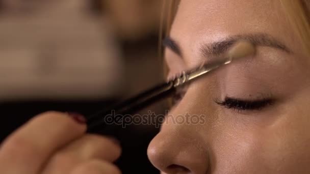 Detalhe de uma jovem mulher aplicando maquiagem com escova. Fecha. Salão de beleza . — Vídeo de Stock