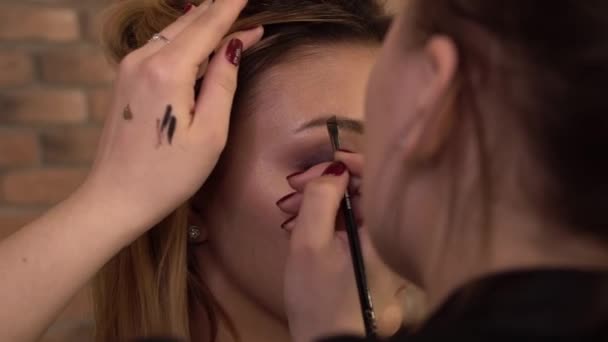 Detail of a young woman applying makeup with brush. Close up. Beauty shop. — Stock Video