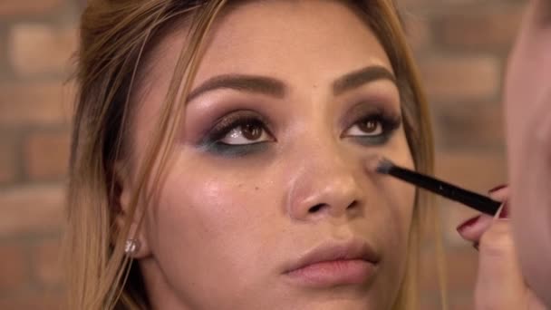 Detail of a young woman applying makeup with brush. Close up. Beauty shop. — Stock Video