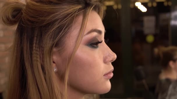 Detail of a young woman applying makeup with brush. Close up. Beauty shop. — Stock Video