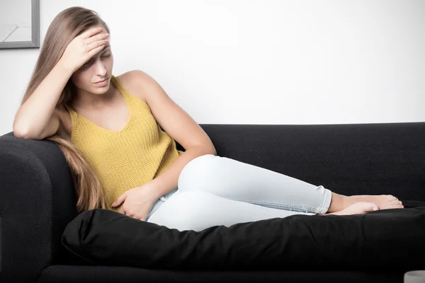 Frau im Schmerz auf einer Couch — Stockfoto