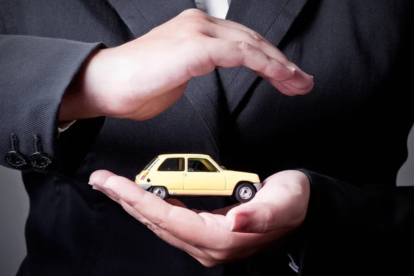 Two hands facing each other, protect a yellow car. — Stock Photo, Image