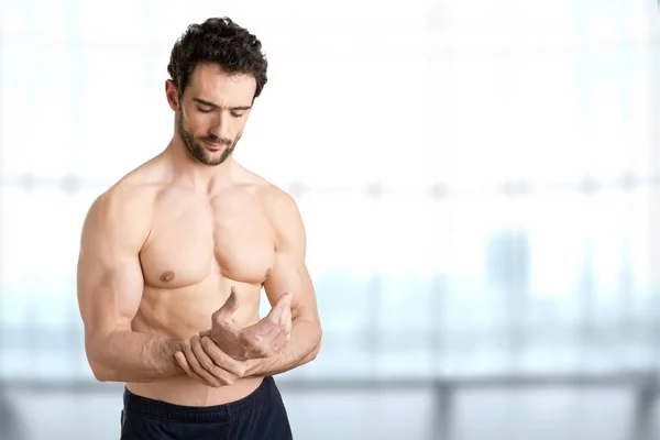 Rüde mit Schmerzen im Handgelenk, vor blauem Hintergrund — Stockfoto