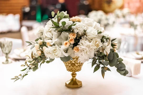 Gelinin sarı ve beyaz çiçekli buketi restoranda düğün hazırlıkları yapıyor. Restorandaki masada beyaz ve sarı şakayık ve güllerden oluşan güzel bir gelin buketi.