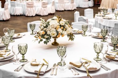 Restoranda beyaz düğün süsü. Lüks düğün düzenlemesi. Düğün ziyafeti dekorasyonu. Restorandaki masalar güzel beyaz şakayıklar ve güllerle süslenmiş.