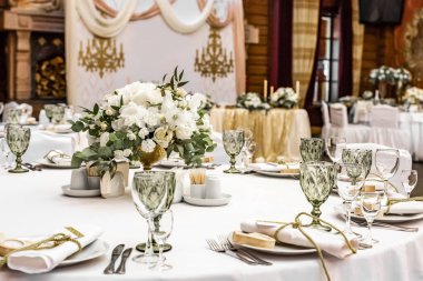 White wedding decoration in restaurant. Luxury wedding arrangement. Wedding banquet decoration. Tables in restaurant decorated with beautiful white peonies and roses clipart