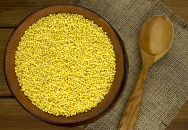 Darı kabuğu çıkarılmış tane yuvarlak pot ve tahta kaşık 