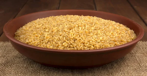 Trigo de bulgur seco em uma tigela de barro no saque — Fotografia de Stock