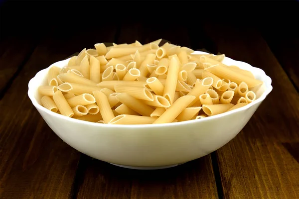 Penne pasta italiana en plato sobre fondo de madera — Foto de Stock