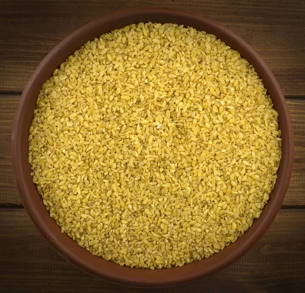 Dry bulgur wheat in a clay bowl on the table — Stock Photo, Image