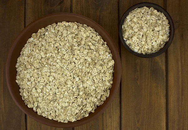 Harina de avena copos de avena seca en cuencos sobre mesa de madera —  Fotos de Stock