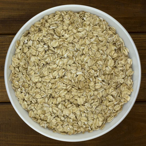 Harina de avena copos de avena seca en tazón sobre mesa de madera —  Fotos de Stock