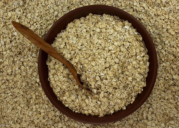 Harina de avena copos de avena seca en tazón en el fondo con cuchara de madera —  Fotos de Stock