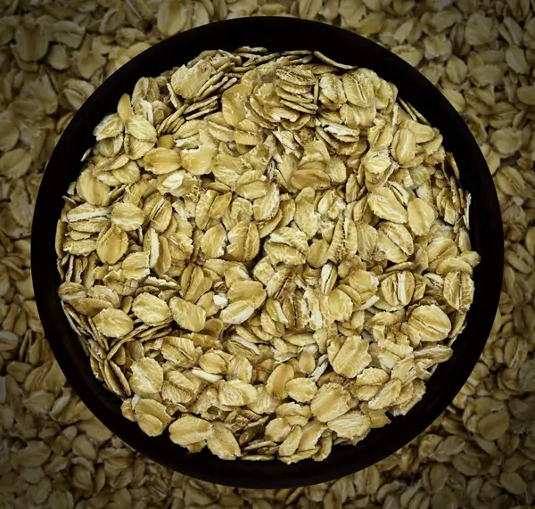 Harina de avena copos de avena seca en tazón en el fondo —  Fotos de Stock