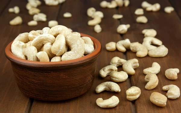 Rohe Cashewnüsse in Schüssel auf strukturiertem Holzhintergrund — Stockfoto