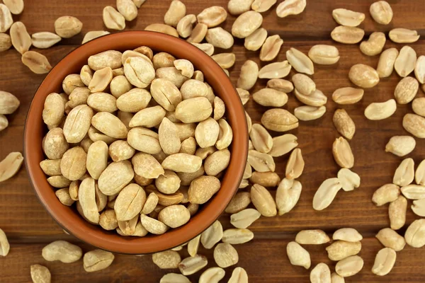 Жареный соленый арахис в миске на деревянном фоне — стоковое фото
