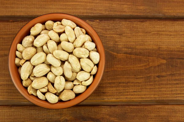 Roasted salted peanuts in bowl on a wooden background — Stock Photo, Image