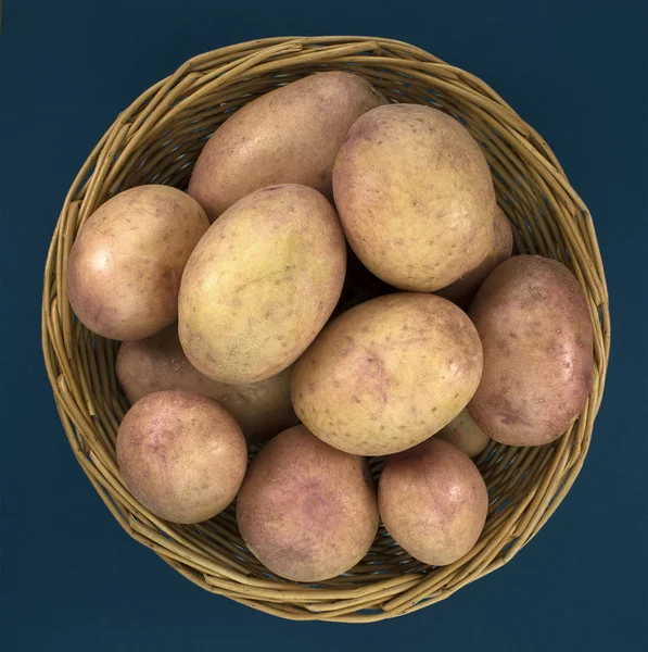 Patatas frescas en canasta sobre fondo azul viejo — Foto de Stock