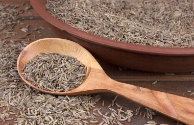 Kimyon. Kimyon tohumları ahşap masa üzerinde. Tahta kaşık Kimyon tohumu