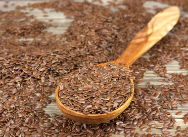 Tahta arka planda tahta kaşıkta keten tohumu.. 