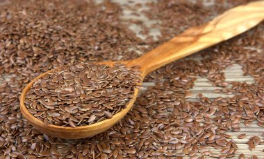 Tahta arka planda tahta kaşıkta keten tohumu.. 