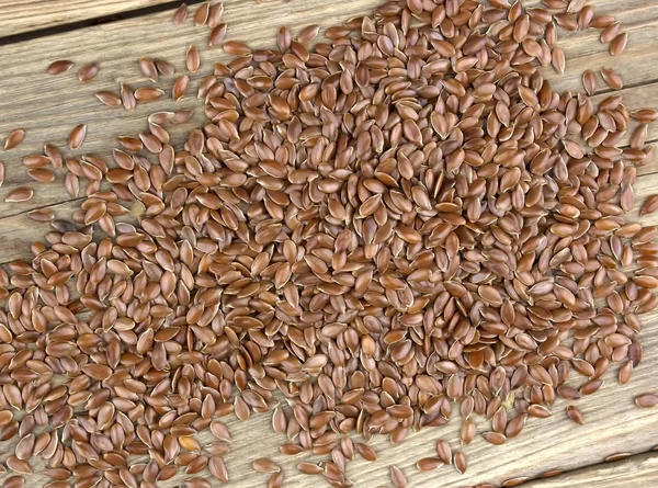 Scattered flax seeds on wooden background.