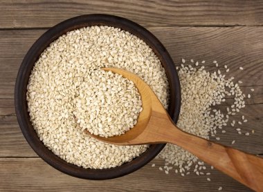 Bir tahta kaşıkla ahşap arka plan üzerinde bir kasede susam