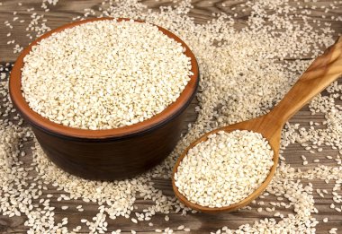 Bir tahta kaşıkla ahşap arka plan üzerinde bir kasede susam