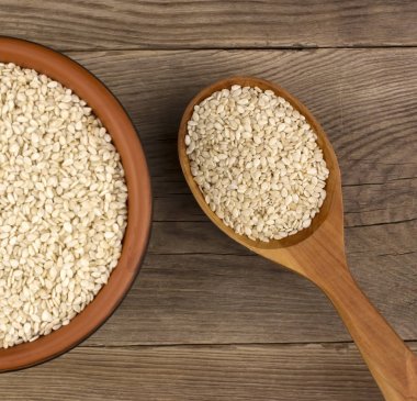 Bir tahta kaşıkla ahşap arka plan üzerinde bir kasede susam