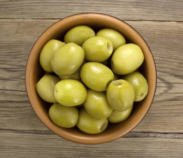 Зеленые оливки в миске на деревянном столе — стоковое фото