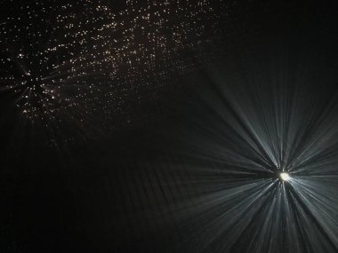 Karanlık bir alanda küçük deliklerden ışık ışınları