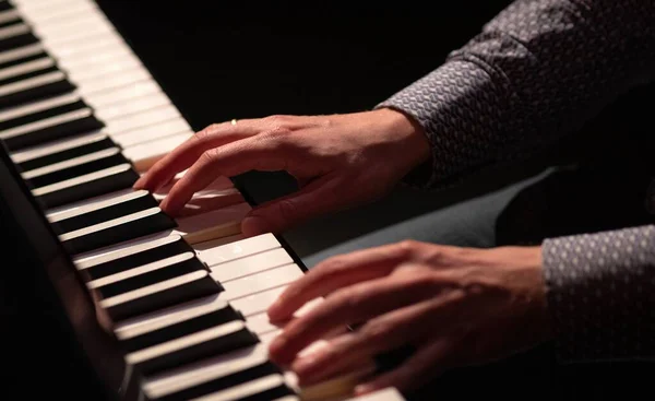 Main jouant du piano dans une blouse de théâtre sombre touches blanches et noires — Photo