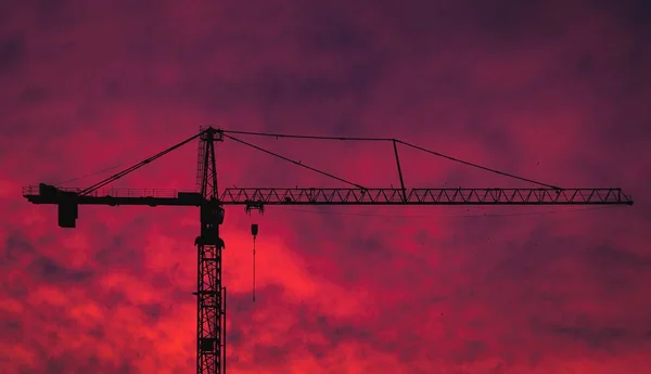 Силуэт крана на фоне красного заката неба — стоковое фото