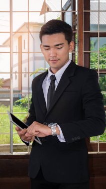 Tablet tutarak ve bilek bakarak Asya iş adamı