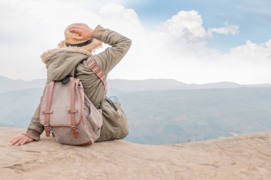 Hippi kız kayalık bir gökyüzü mavi karşı dağın zirvesine oturan sırt çantası ile