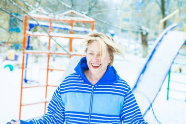 Aktif, sarışın bir kadın antrenman yapıyor ve ısınma egzersizini açık havada, karlı havada ip atlarken yapıyor.