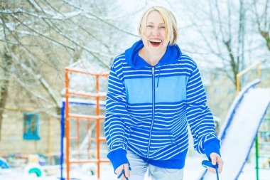 Aktif, sarışın bir kadın antrenman yapıyor ve ısınma egzersizini açık havada, karlı havada ip atlarken yapıyor.