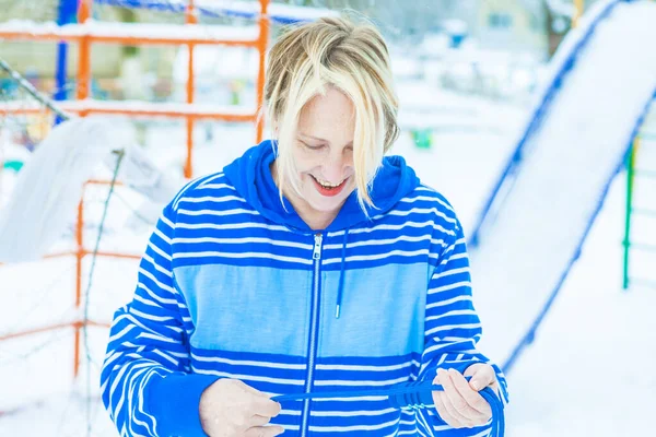 Aktif, sarışın bir kadın antrenman yapıyor ve ısınma egzersizini açık havada, karlı havada ip atlarken yapıyor.