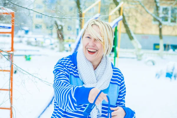 Aktif, sarışın bir kadın antrenman yapıyor ve ısınma egzersizini açık havada, karlı havada ip atlarken yapıyor.