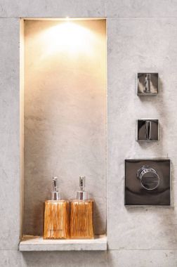 Ham beton duvar ile tasarlanmış banyo şişe raf ve krom Duş Vana ile dekore edilmiştir.