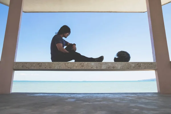 Kaskını için seyir deniz yanında çatı altında oturan bir Asyalı adam