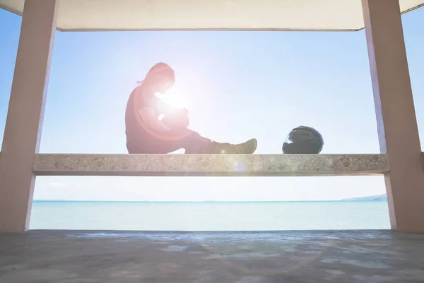 Kaskını için seyir deniz yanında çatı altında oturan bir Asyalı adam