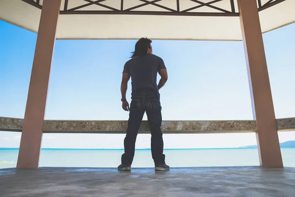 Bir Asya adam stand çevirmek çatı altında sırt yanında gelen tekne bekliyorum deniz